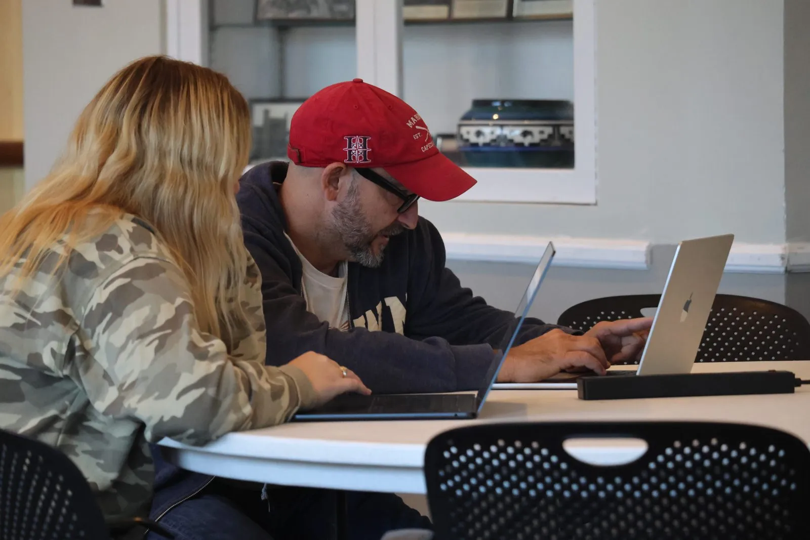 Two participants work on laptops at a round table.