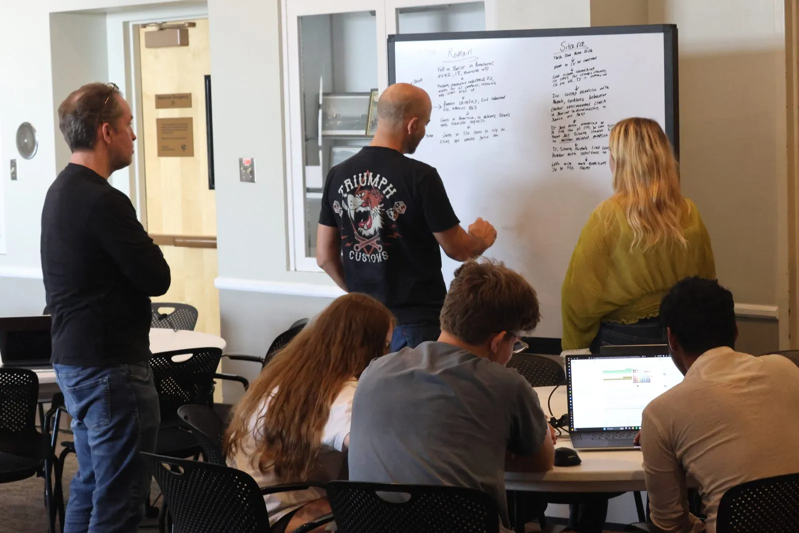 A team plans its story at a whiteboard with a mentor.